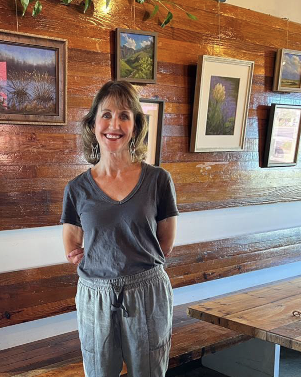 Joan stands in front of her paintings 