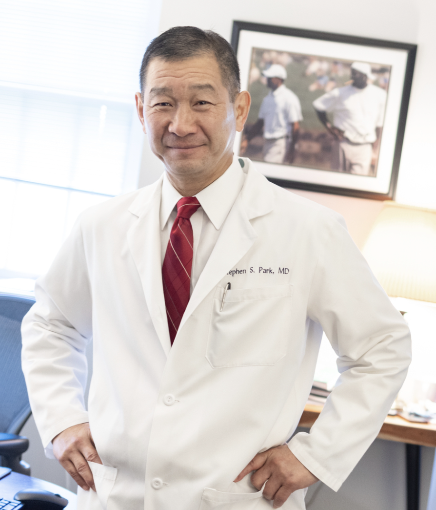 Dr Park stands in his white coat with hands on hips 
