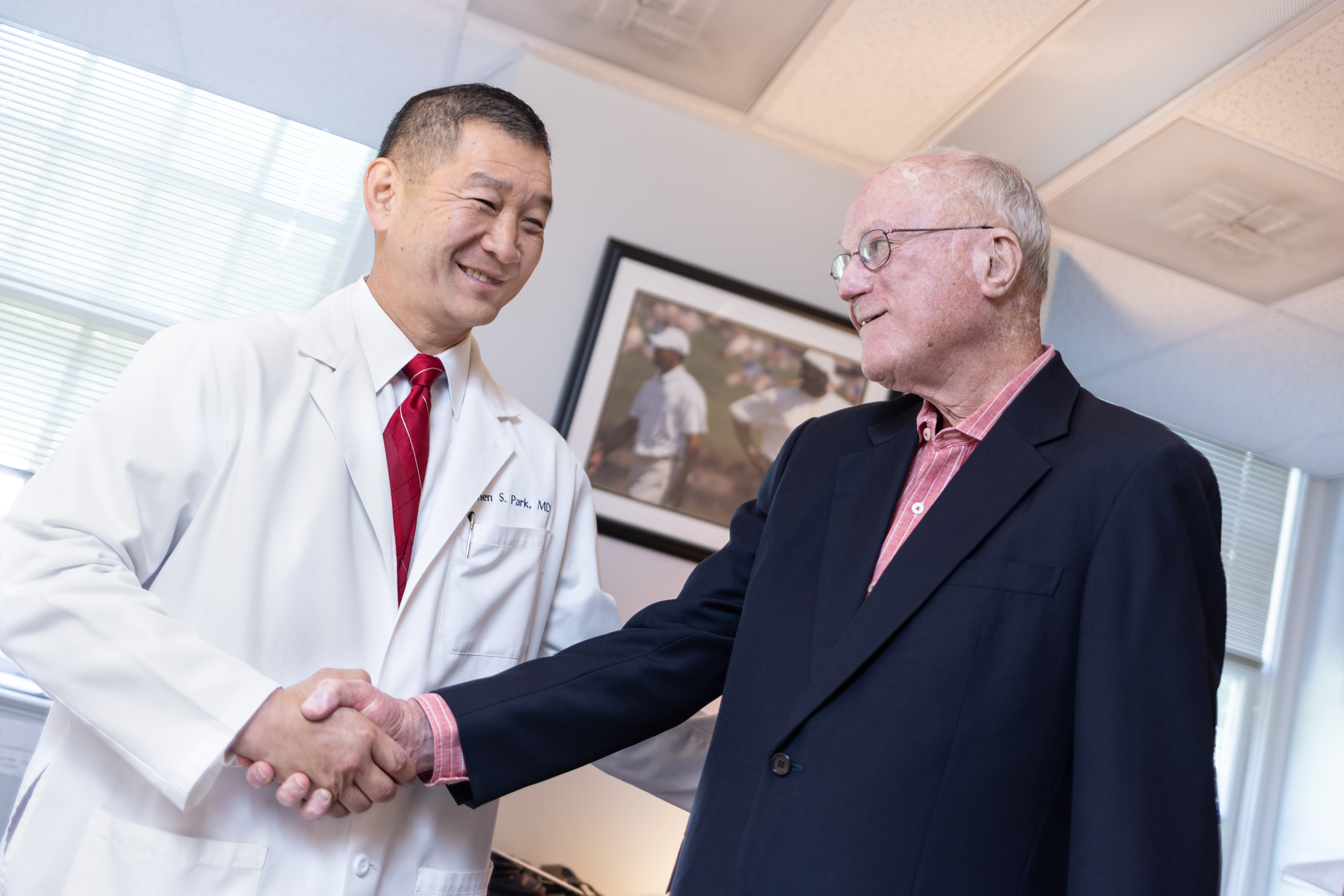 Dr. Park and Jack Reid stand in an office shaking hands