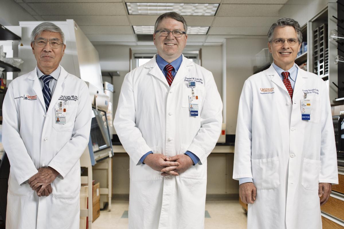 From left to right: Dr. Larry Lum, Dr. Trey Lee, and Dr. Craig Slingluff stand in their lab in their white coats