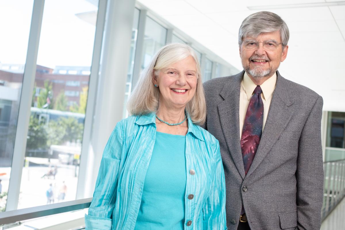 Martha and Dr. Geoffrey Weiss stand in a hallway overlooking UVA Health.