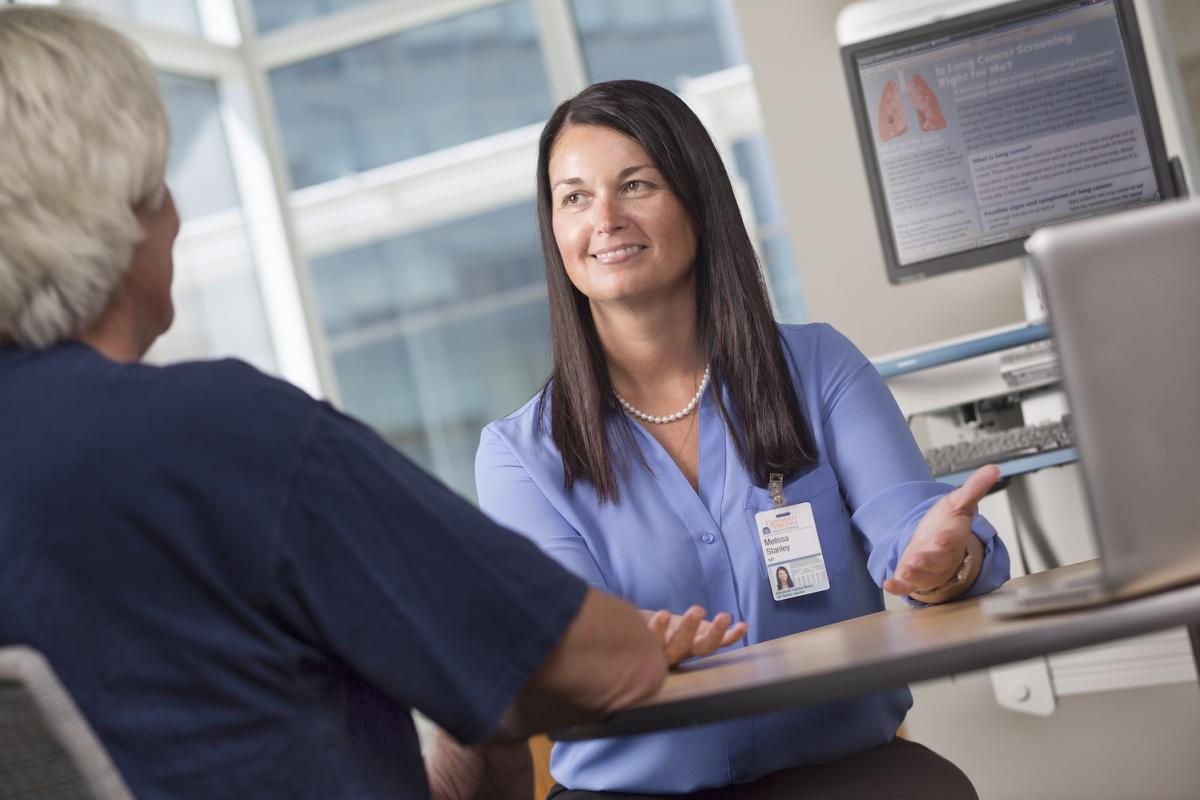 Nurse Melissa Stanley sits at a desk consulting with a patient