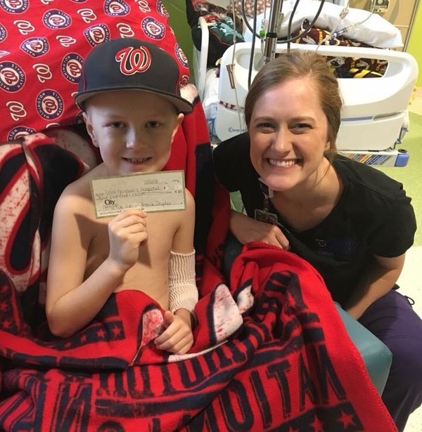 Parker Staples gives UVA Child Life Specialist Kristina Berg a check for the proceeds of his bracelet fundraiser.