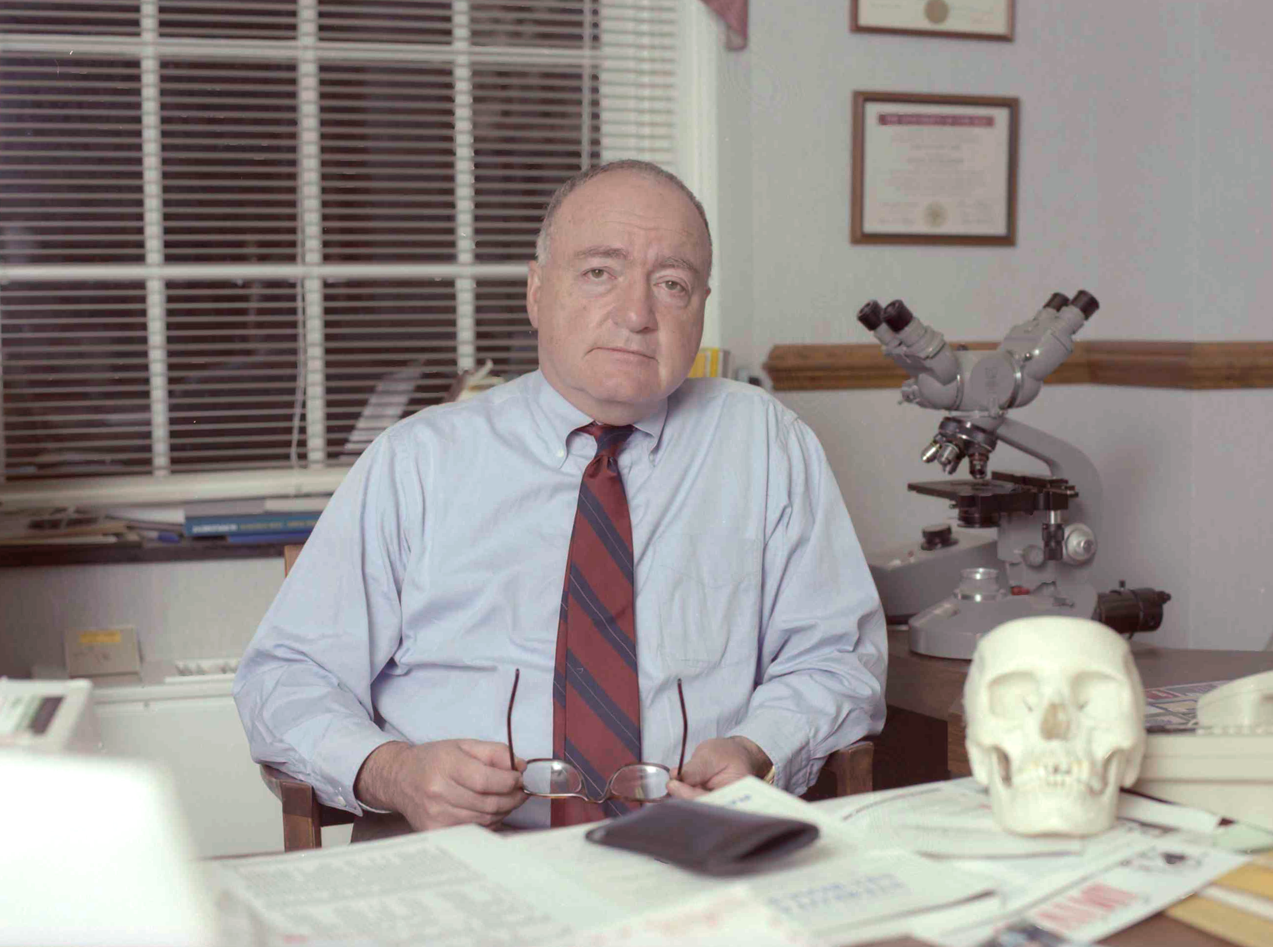 Dr. John Jane sits at his desk. 