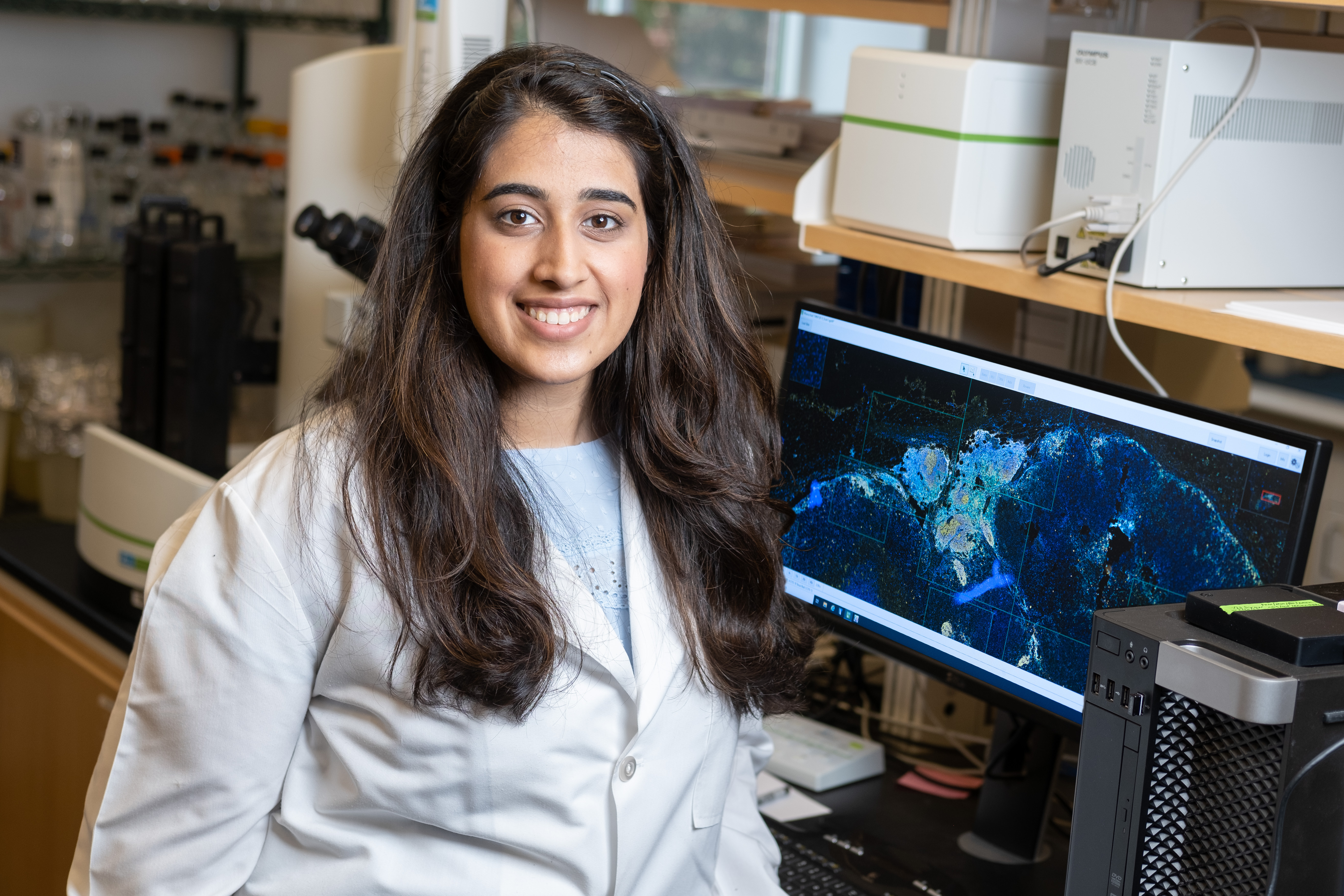 Priya Katyal sits in front of computer in white coat 