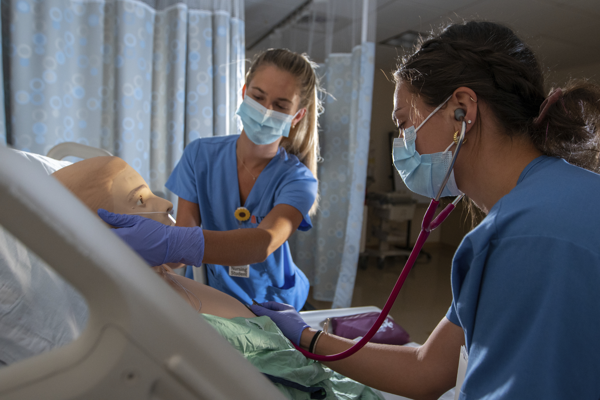 two students practicing with a medical simulation mannequin 