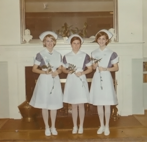 three women stand in nursing uniforms