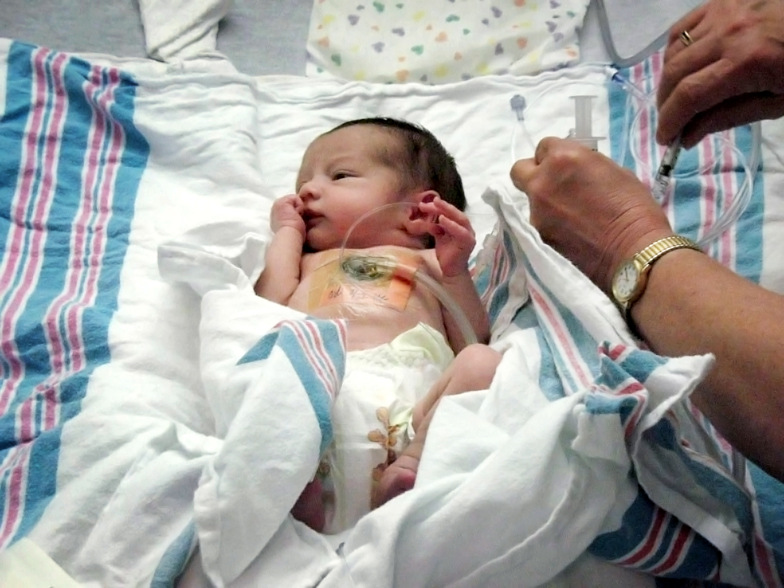 Olivia as an infant laying in a NICU bed with hospital blankets