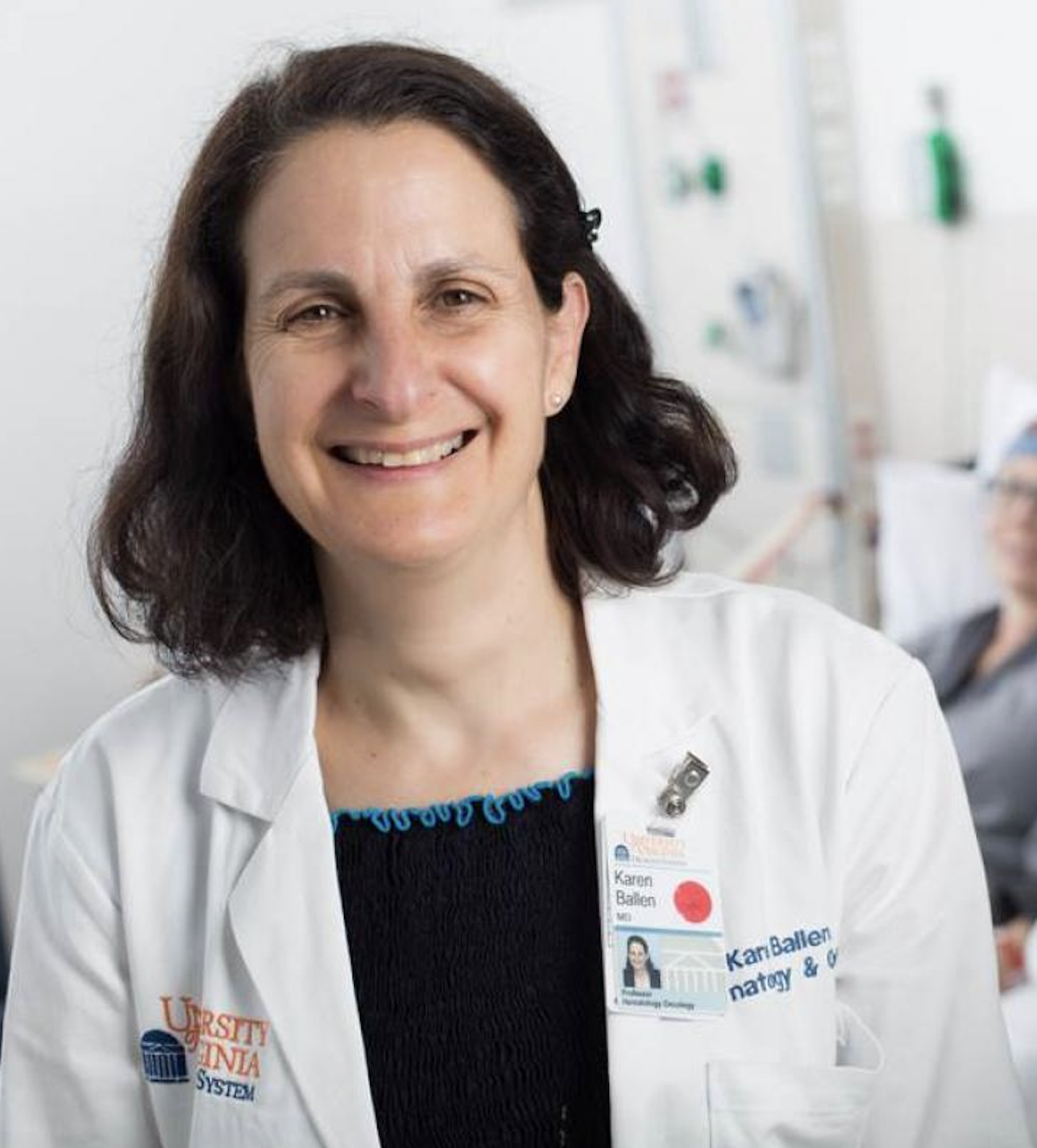 Dr. Ballen stands smiling in a white coat