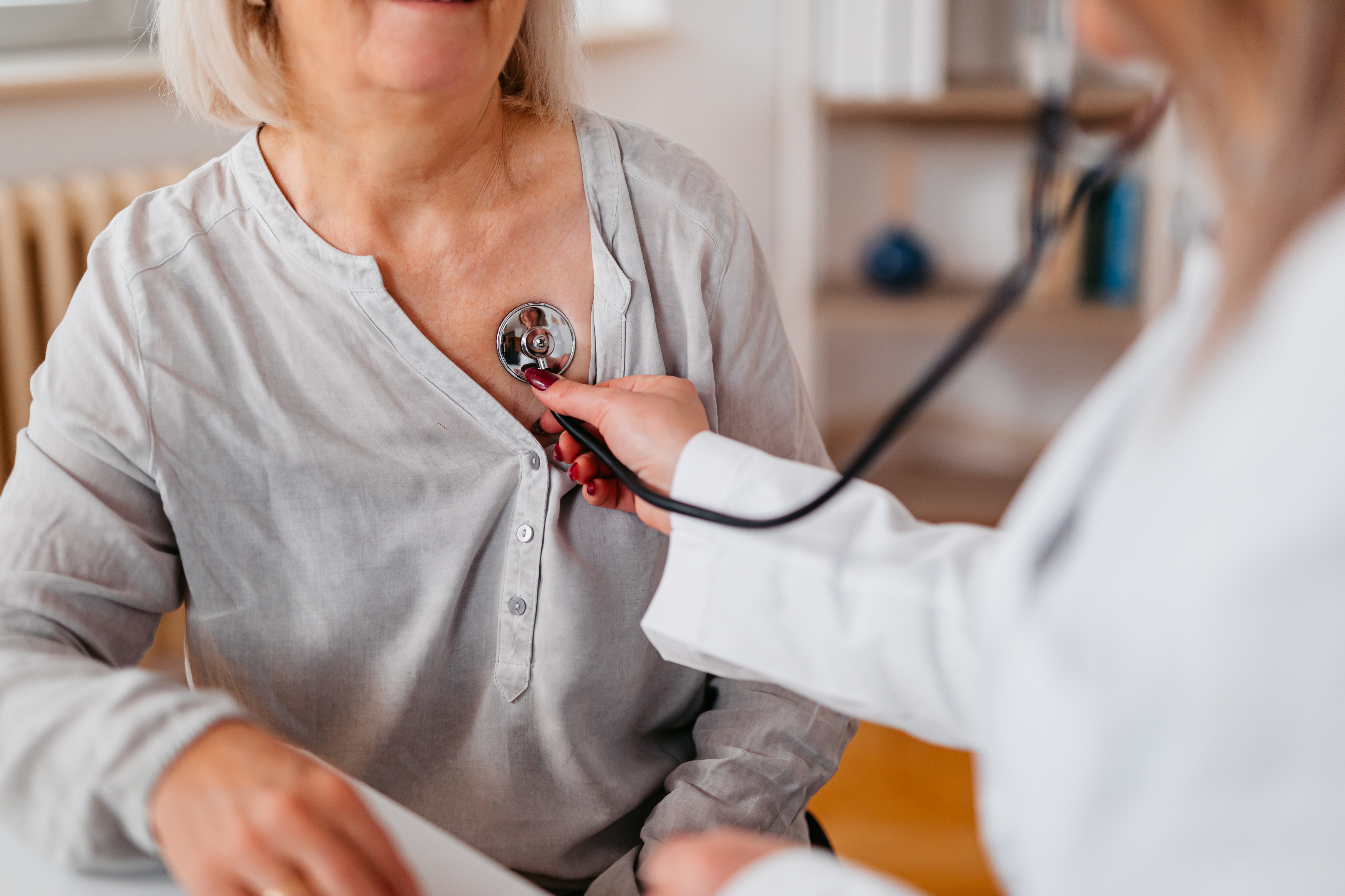 doctor holds stethoscope to patient 