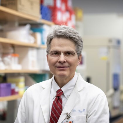 Dr. Slingluff stands in his lab wearing a white shirt and red tie. 