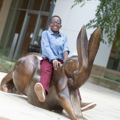 Kahmari sits on a statue of a rabbit 