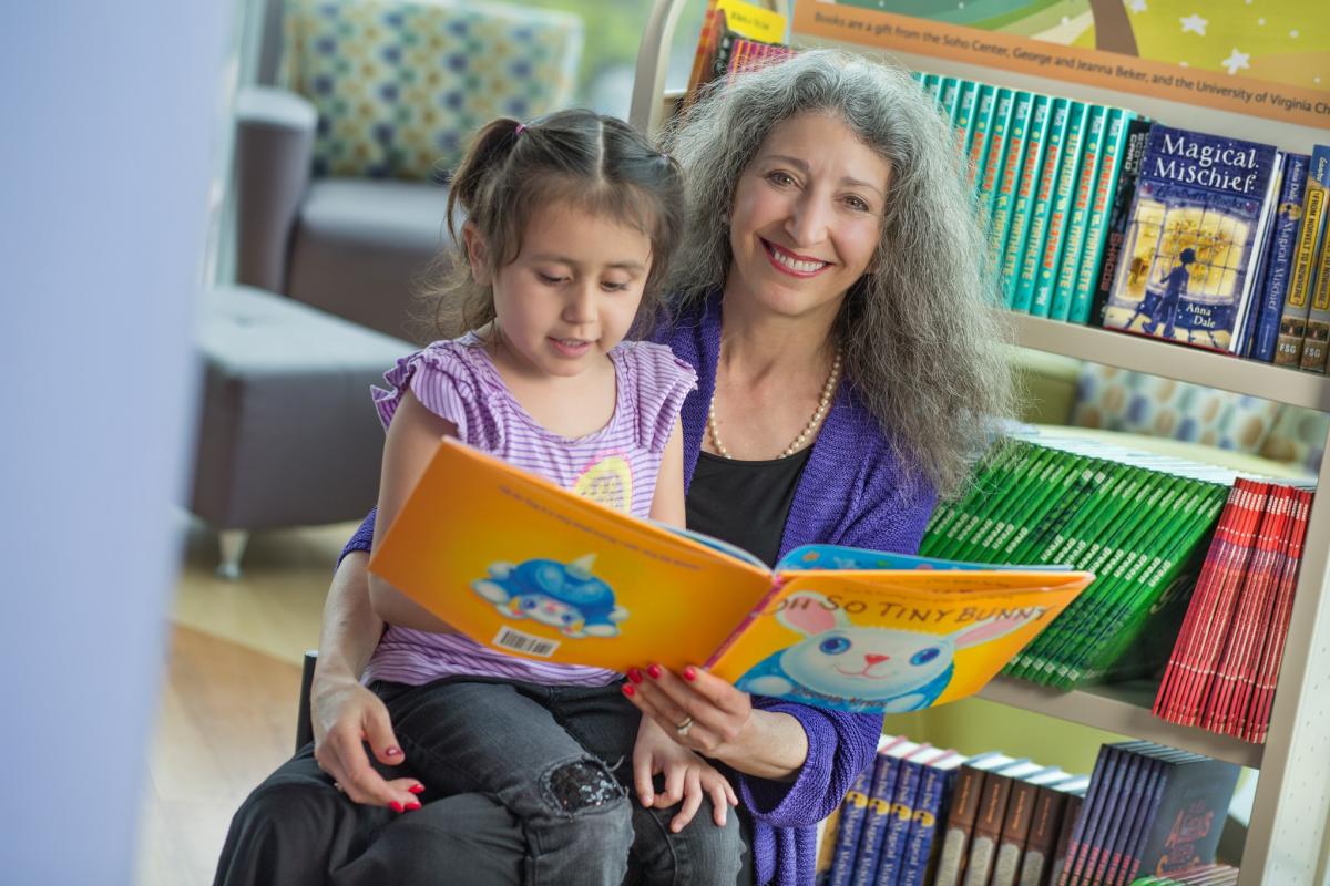 Soho Center Founder and Director Jeanna Beker shares a donated book with four-year-old Allison Valle.