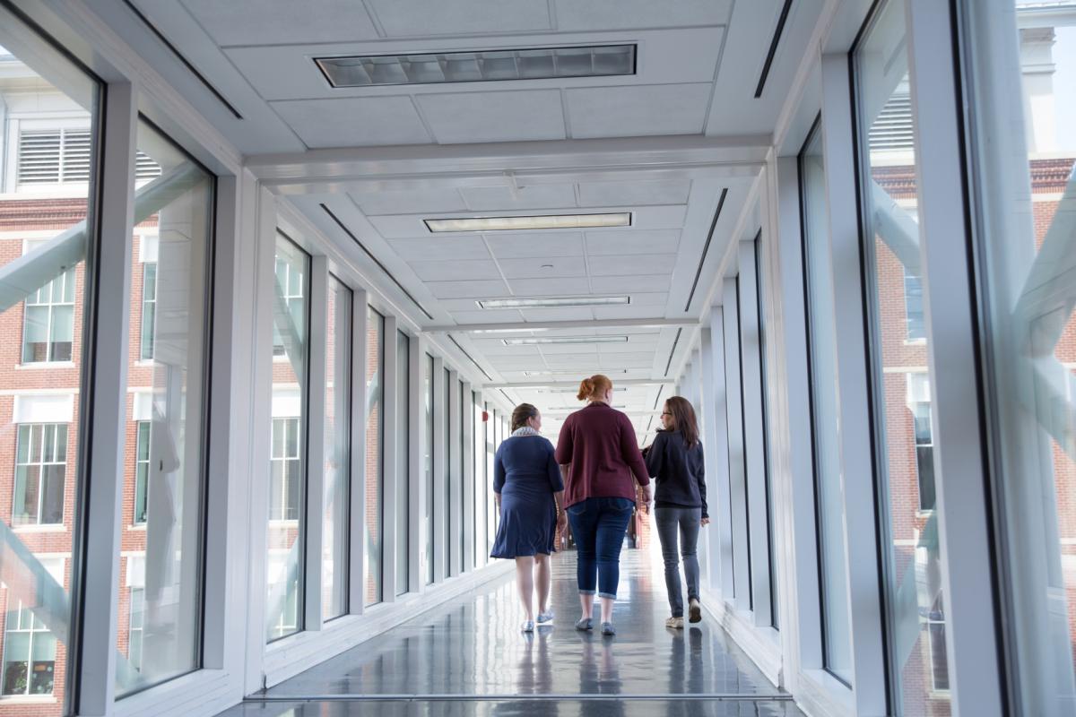 Three women walk through a glass link to get the UVA School of Medicine building.