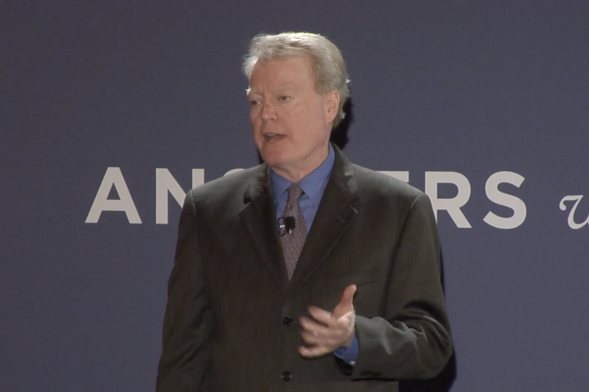 Dr. Loughran stands on a stage and speaks.
