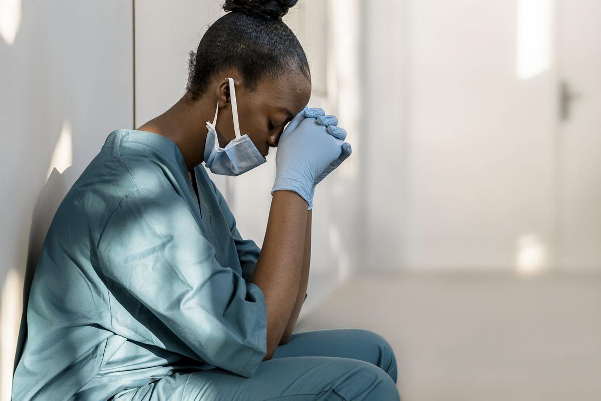 Nurse sits with head in hands