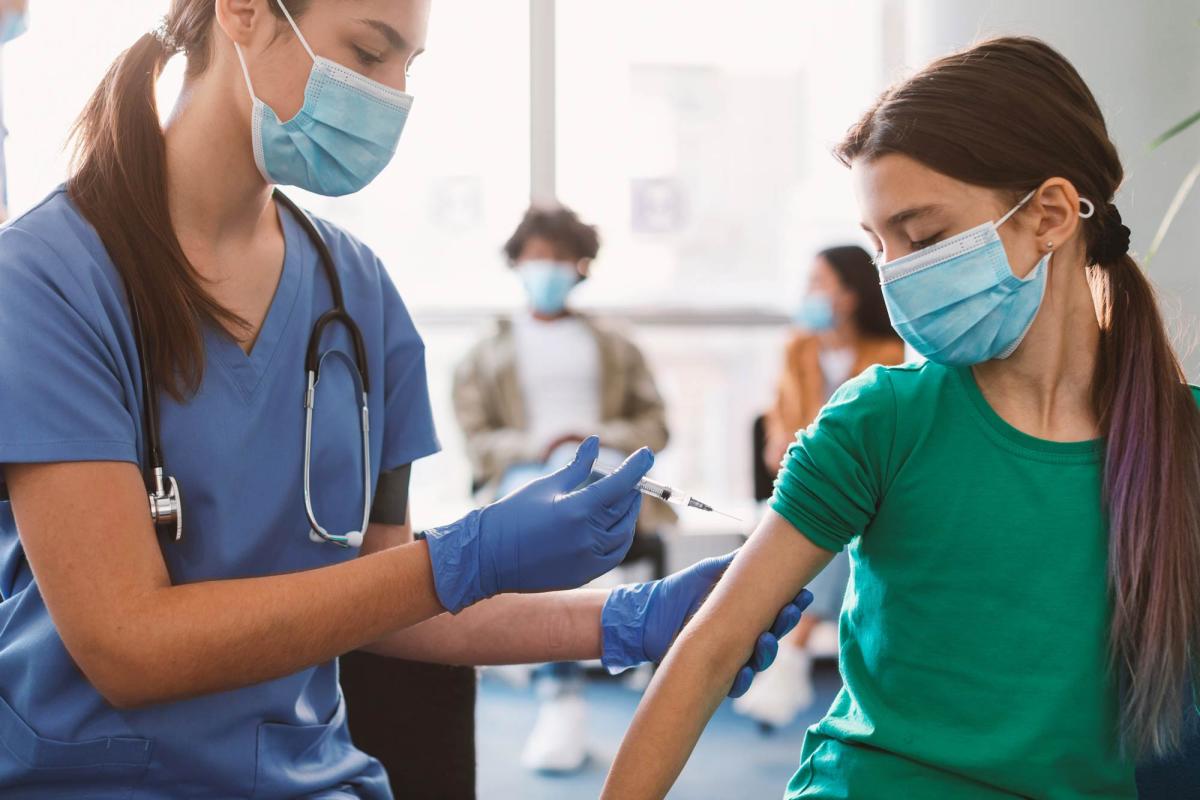 young girl receives vaccine from healthcare worker