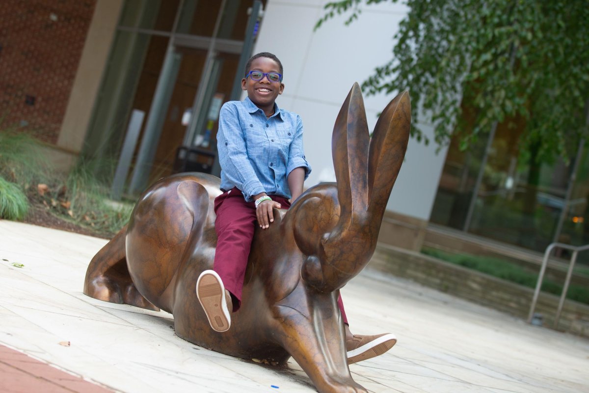 Kahmari Riedl, a 13-year-old patient, on statue in front of uva children's