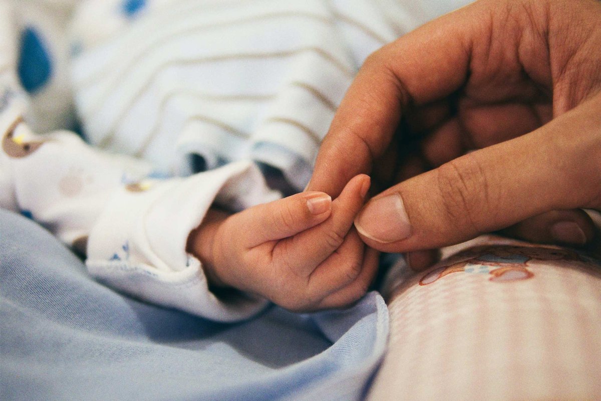 infant's hand being held by an adult's hand