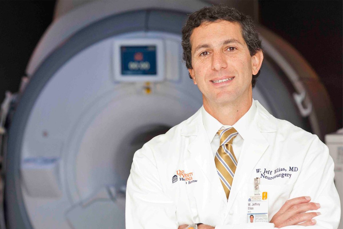Dr. Elias stands in white coat in front of focused ultrasound machine