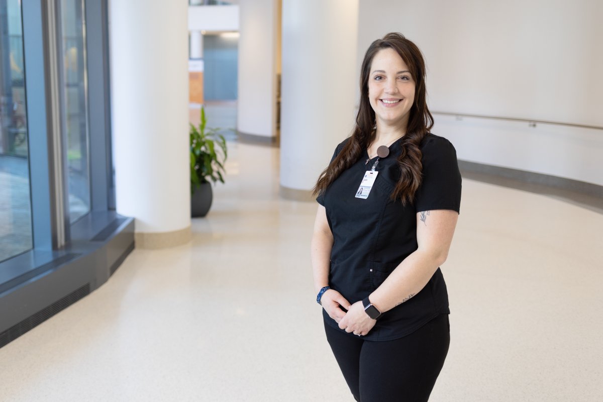 Caitlin stands in a hallway wearing scrubs