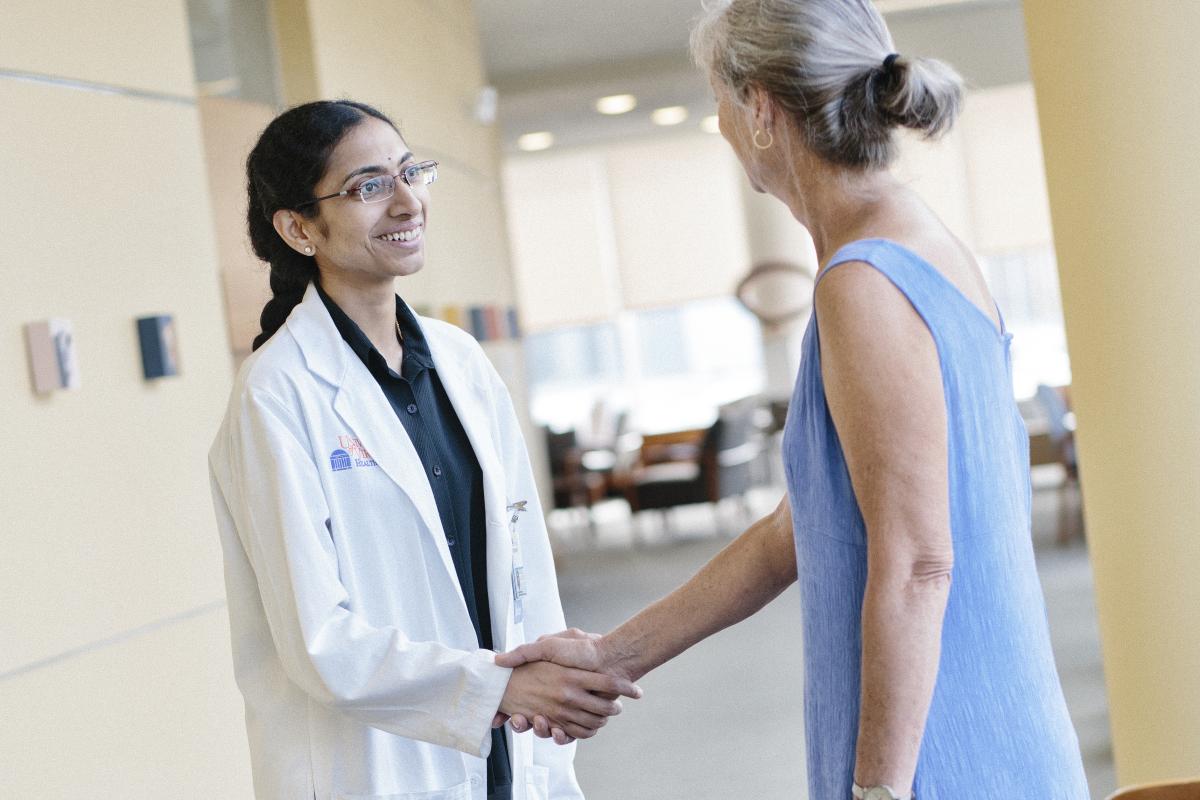 Dr. Indumathy Varadarajan shakes the hand of a patient in a blue dress.