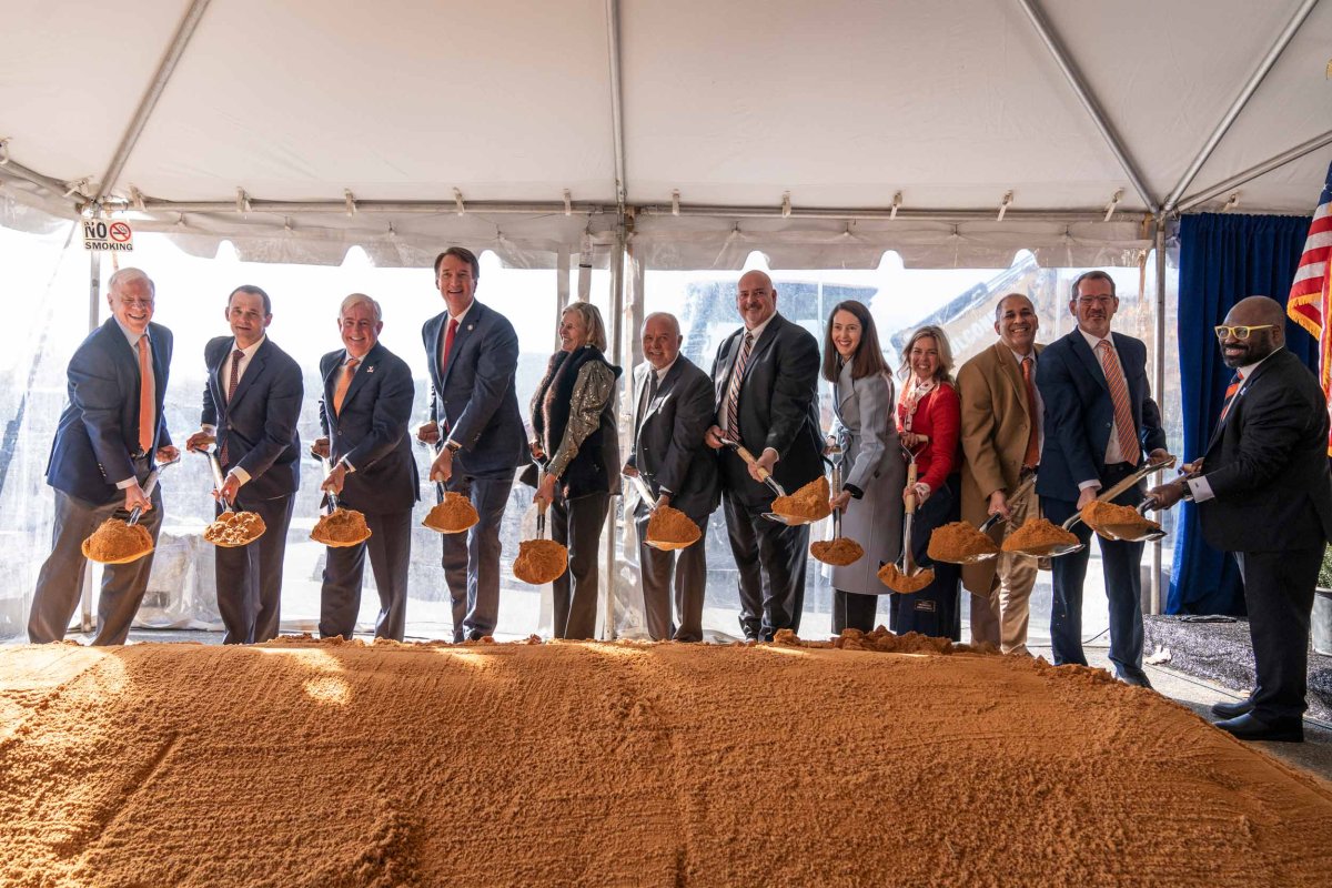 Group stands at a pile of dirt holding shovels