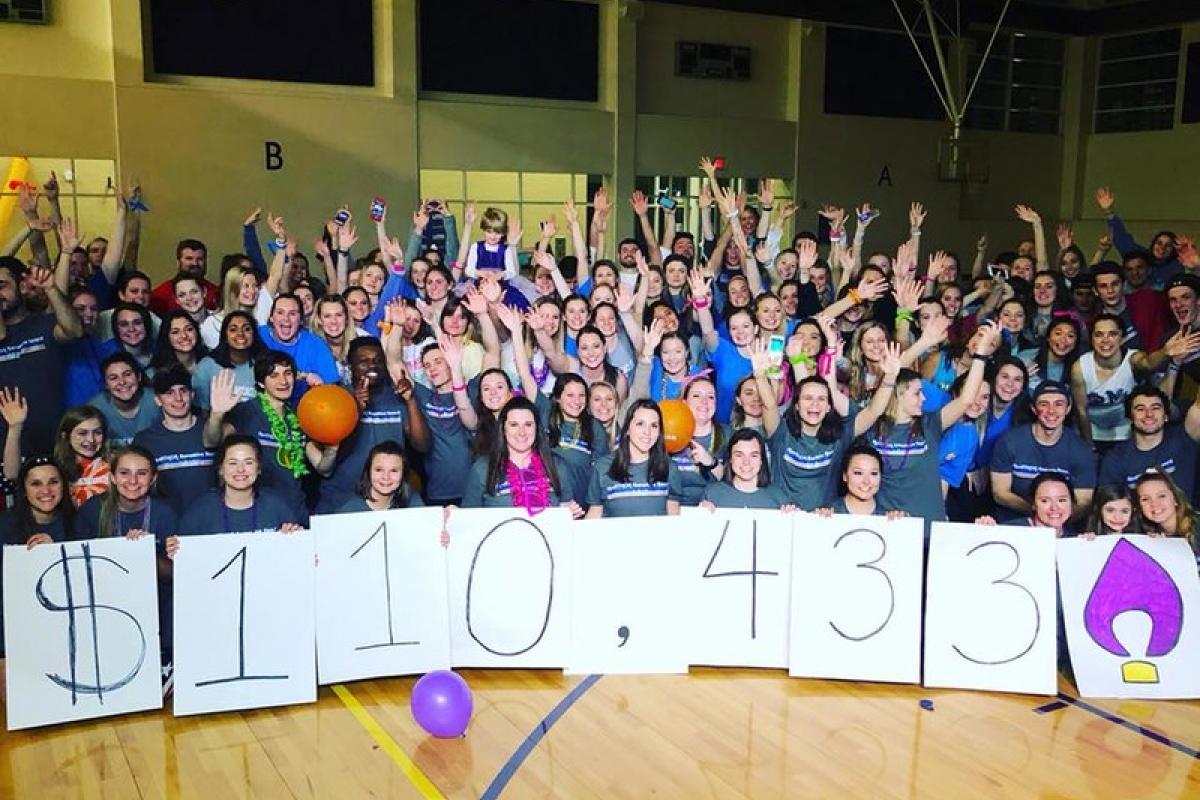 A group of JMU students hold up signs reading how much they've raised during a dance marathon supporting UVA Children's Hospital.