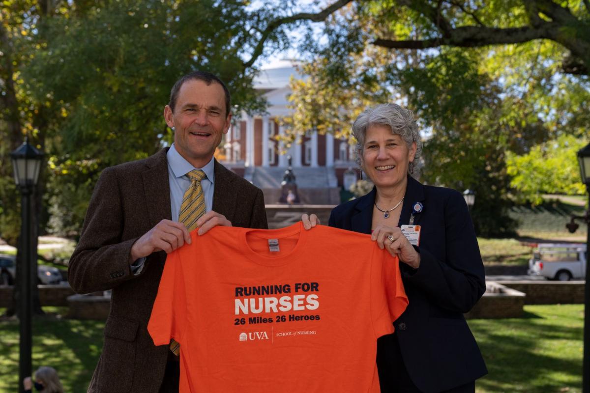 President Jim Ryan and School of Nursing Dean Pam Cipriano stand side by side in front of rotunda with a Running for Nurses shirt