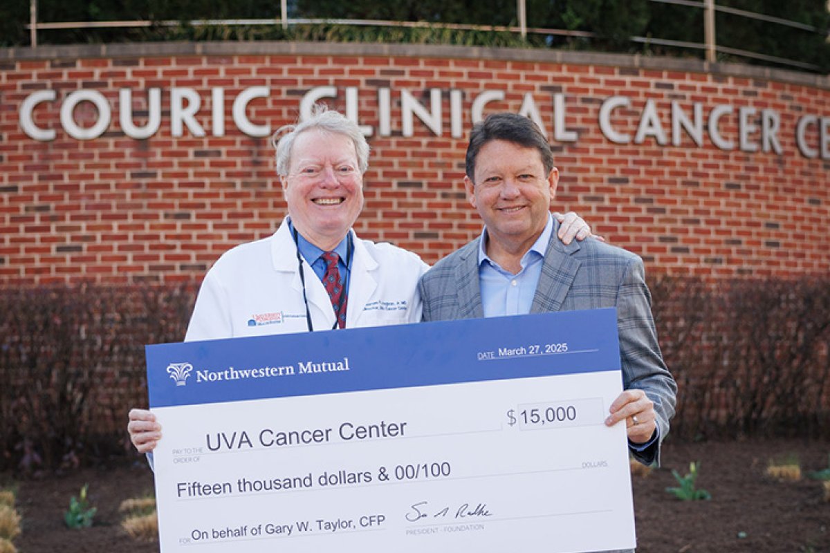 Loughran and Taylor stand outside holding a giant check