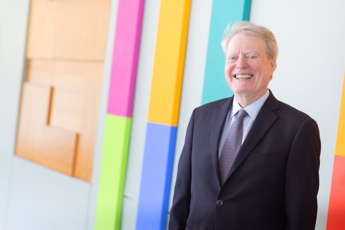 Dr. Loughran stands in front of colorful artwork, smiling