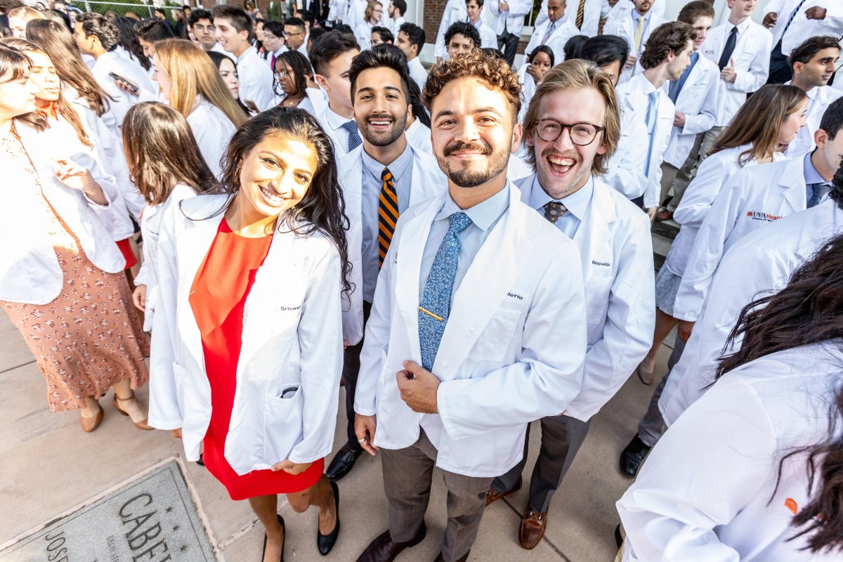 students stand in their white coats smiling 