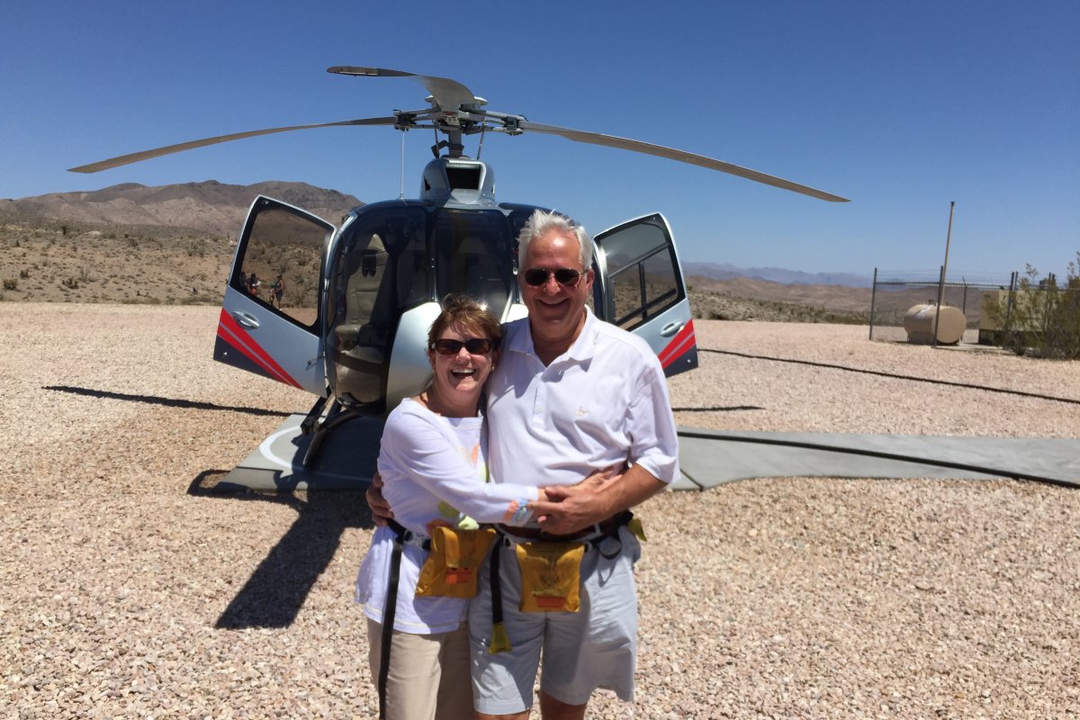 the couple stands in front of a helicopter
