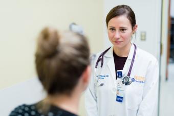 A female neurologist listens intently to her patient in a consult room.